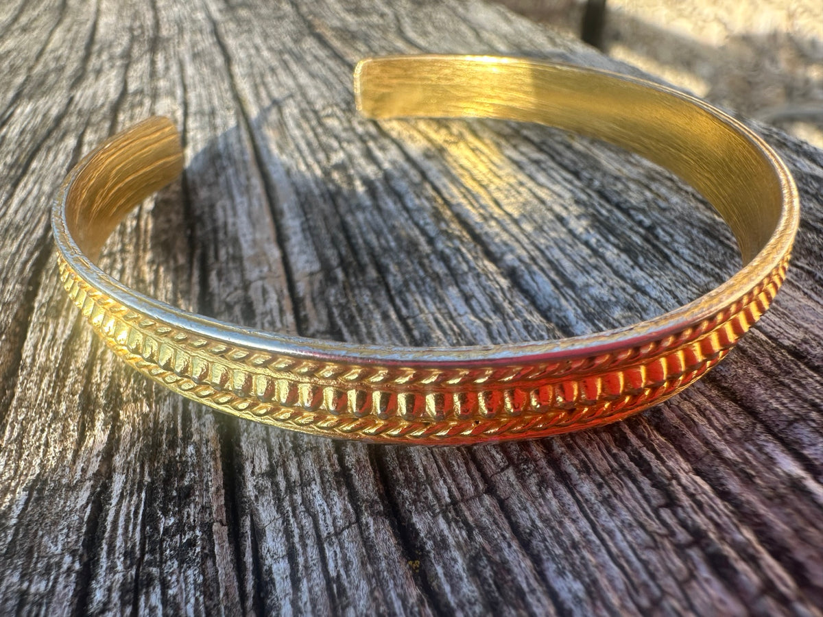 Aloka Radiate Cuff in natural sunlight on weathered wood