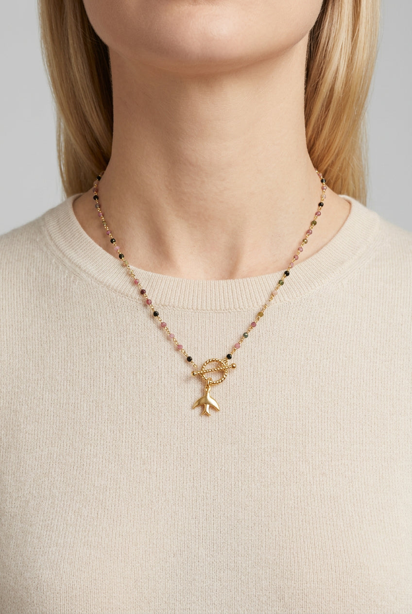 Freedom beaded bird necklace with multicoloured beads and a golden toggle fastening, worn close up