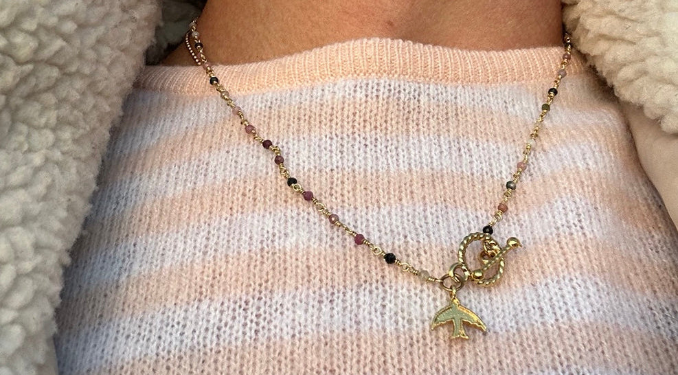 Freedom beaded bird necklace worn with a pale striped jumper