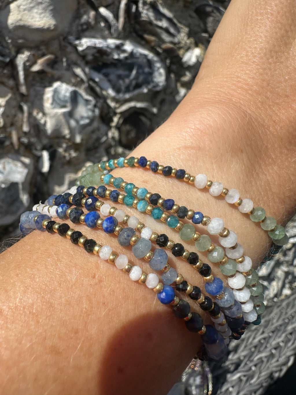 Blue and green gemstone bracelets worn in a stack