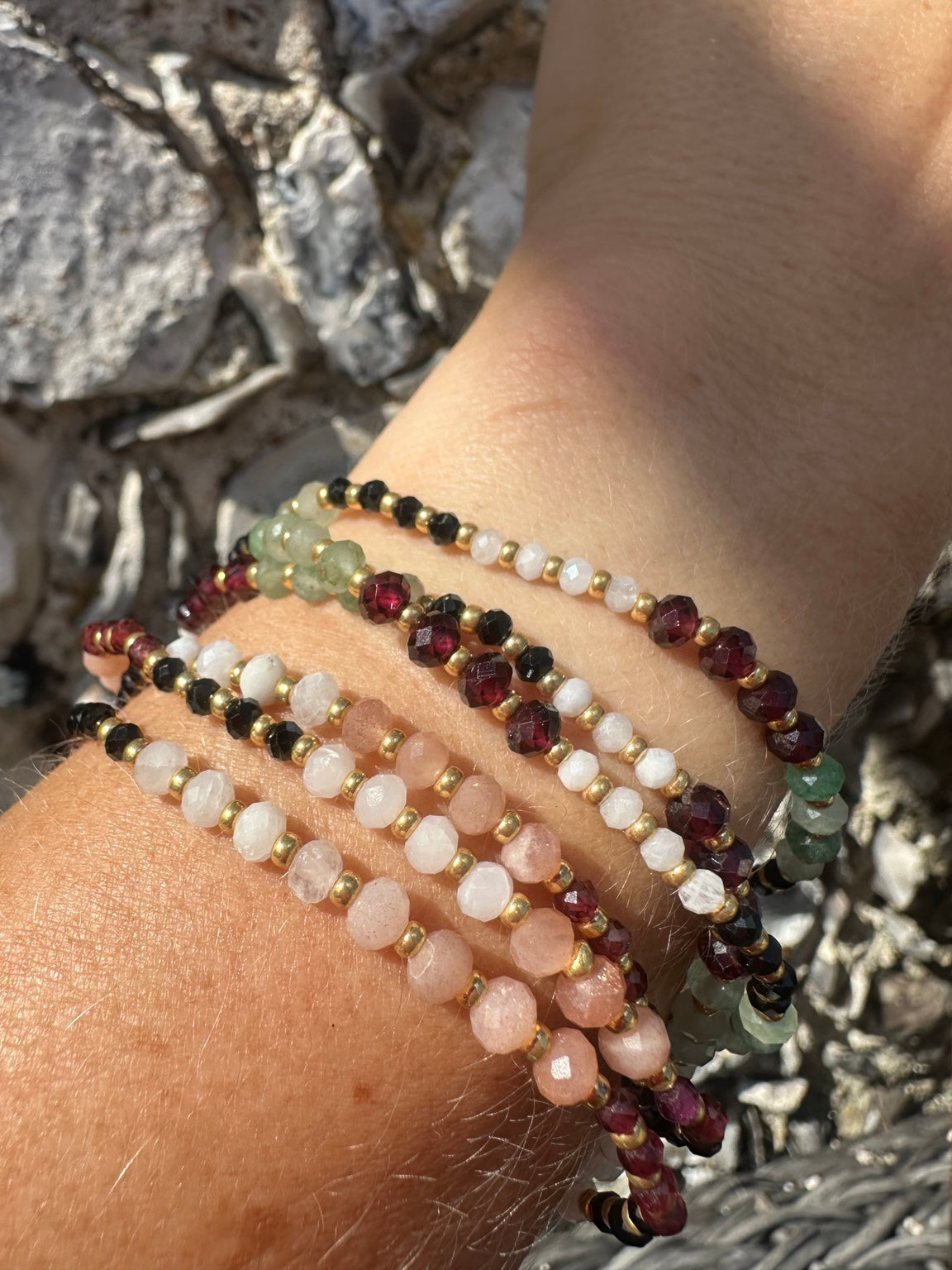 Pink and garnet gemstone bracelets worn in a stack